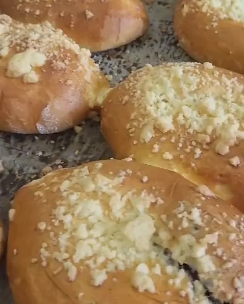 Upieczone jagodzianki z kruszonką na blasze, w pęknięciach widać jagody.